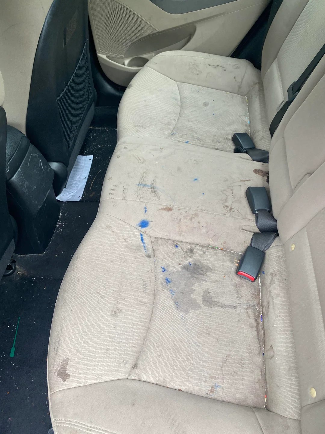 Vehicle back seat before professional detailing showing areas needing attention